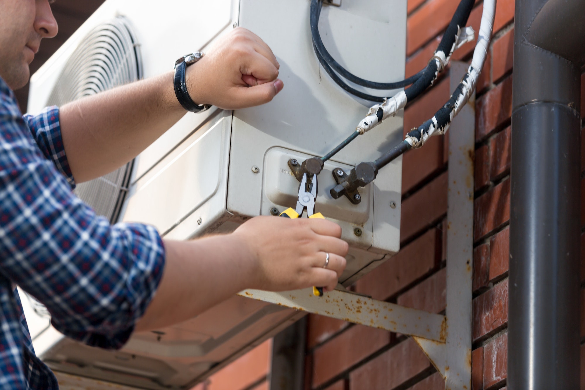 Closeup of male technician repairing outdoor air conditioner unit